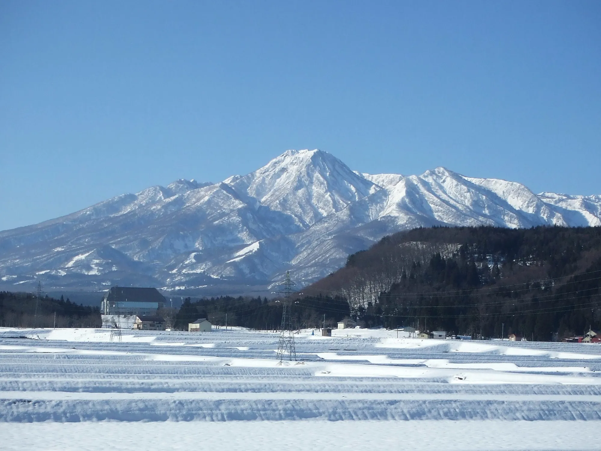 雪をかぶった妙高山と、雪に覆われた妙高の田園